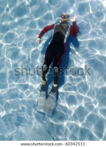 motion blurred free diver giving a ALL OK sign while swimming under water