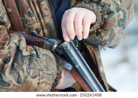 Close-up of a hunter loading his old russian double-barreled side by side shotgun in winter forest