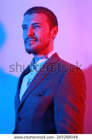 Portrait of handsome casual stylish young man in suit in blue and red colored lights