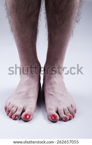 Man\'s Feet with Red Nail Polish and Hairy Legs on Bright Gray Background