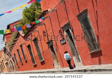 Mexican man passing in front of colorful colonial buildings in Zocalo Street of San Miguel De Allende, Mexico.