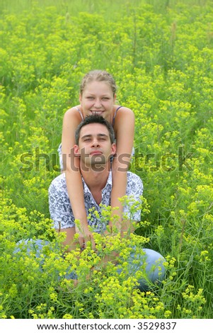 Young smiling couple in the green grass field, portrait orientation