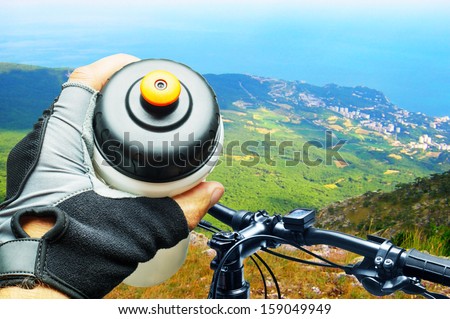 Biker in mountains drinking from water bottle