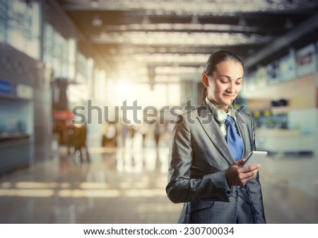 Business woman stands looking at her phone