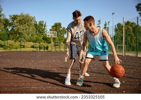 Image, Stock Photo Young man playing basketball on outdoor court.