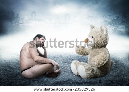 Strange naked man looks at toy bear