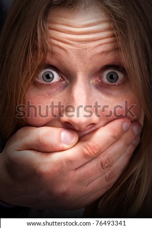 Afraid young girl with closed mouth by hand
