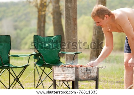 Man grilling shish kebab outdoor in park