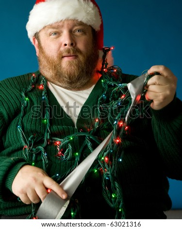A man in a santa hat tangled in a string of lights