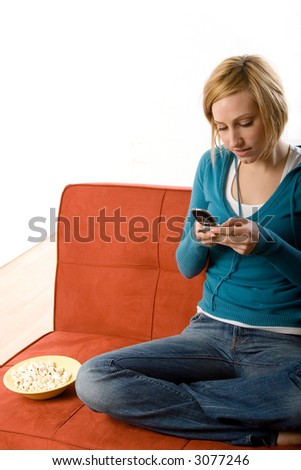 Young woman dialing or typing on a cell phone while sitting on a couch