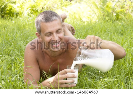 The man is drinking fresh milk in the summer garden