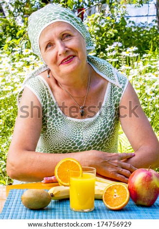Elderly Woman in a summer garden with fresh food on the table