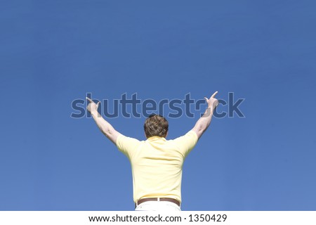 Man raises arms and points with his fingers under a blue sky