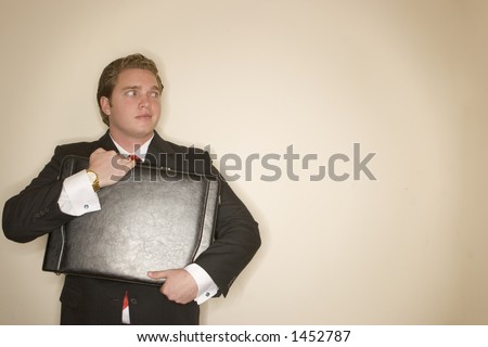 Business man in black suit, white shirt, and red tie holding briefcase making an expression