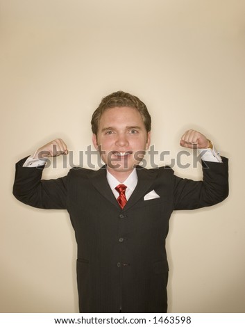 Business man in black suit, red tie, and white shirt is flexing both of his arms