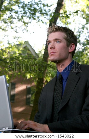 Blond hair blue eye business man is typing on his laptop in the middle of a park