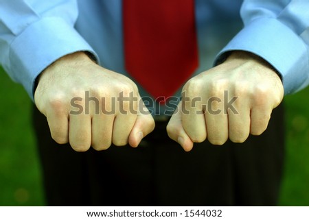 Businessman in blue shirt and red tie holds out both hands, closed as to give the viewer a choice as to which one he/she wants to open