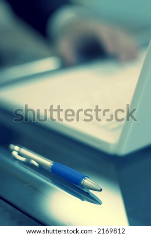 Businessman working on his desk with the focus on the foreground of the pen
