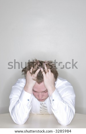Businessman Frustrated sitting at his desk with his fingers in his hair pulling his hair
