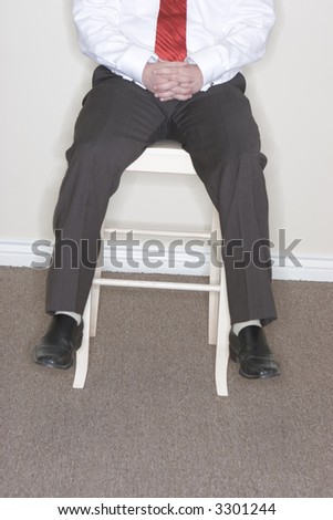 Businessman sitting on a high chair dangling his feet off the chair