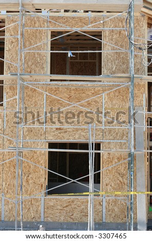 Construction site with scaffolding and exposed wood of a new house focused on the open windows