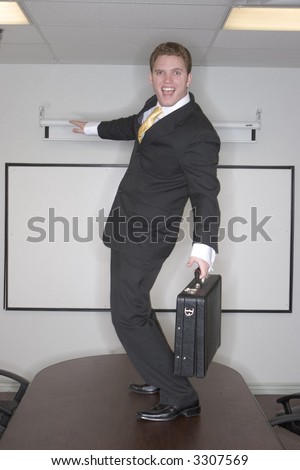 Businessman surfs on the conference table in the office having fun and a good time