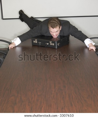 Businessman jumps on the conference table and his briefcase in the conference room