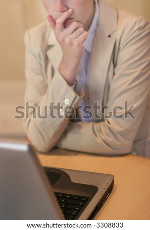 Businesswoman using her laptop on the table with her hand on her chin while pondering