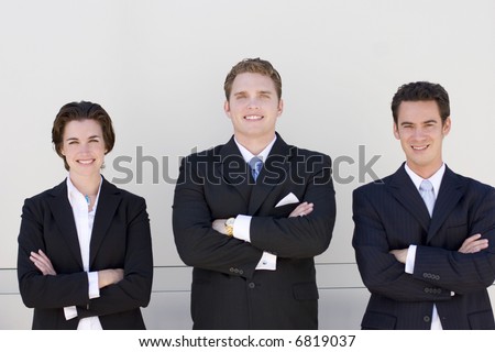 three business people standing side by side looking at camera smiling with white background