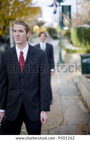 two businessmen staggered one behind the other in full suits