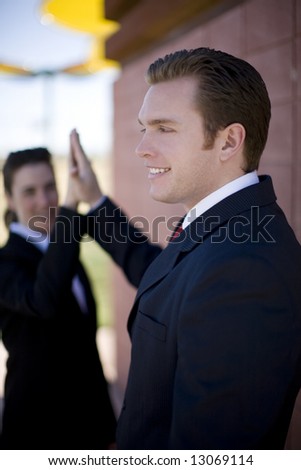 businessman and businesswoman in suits smiling giving high-five