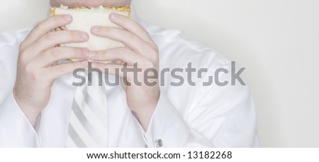 businessman is holding a sandwich to his face while he gets ready to eat for lunch