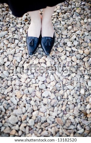 close view of businesswoman formal shoes on rocks