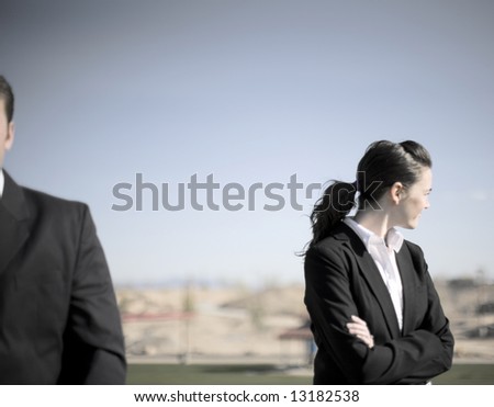 businessman and businesswoman standing together while woman looks away