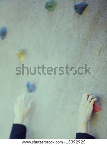hands of single businesswoman climbing up steep wall reaching out with one hand