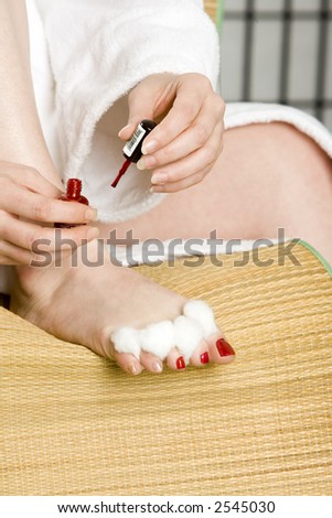 Woman putting red nail polish on her toe nails