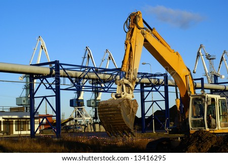 Hydraulic excavator at work. Shovel bucket and cranes against blue sky
