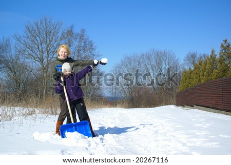 mother and her daughter shoveling and throw up snow on a winter background