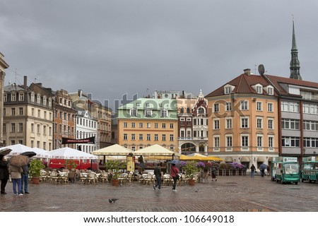 RIGA, LATVIA - JUNE 02: Pedestrians walk under the rain around Dome Square on June 02, 2012 in Riga, Latvia. The Dome Square development started in the end of the 19th century and continued till 1936.