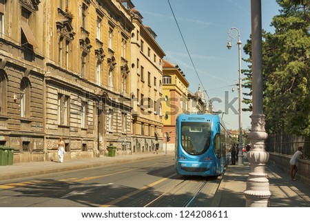 ZAGREB, CROATIA - AUGUST 21: People walk along city street with old houses and travel by tram in Zagreb, Croatia on August 21, 2012. Zagreb Tram run by the Zagrebacki elektricni tramvaj (ZET).