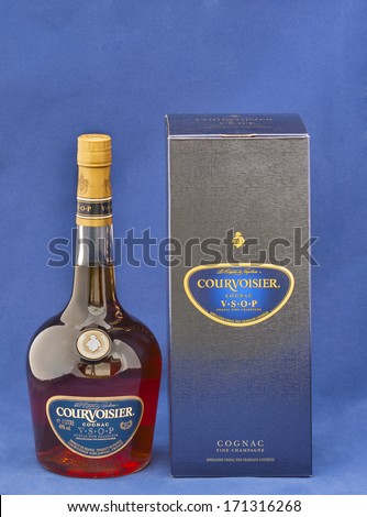 KIEV, UKRAINE - MAY 06, 2012: Courvoisier V.S.O.P. (very superior old pale) Cognac bottle and box against blue. It is a luxury brand of French cognac established by Felix Courvoisier in 1835.