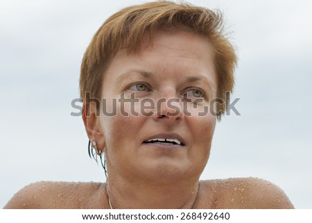 smiling middle aged caucasian tanned naked woman outdoor portrait after sea bathing