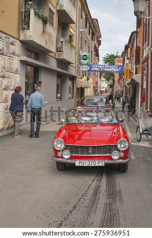 NOVIGRAD, CROATIA - SEPTEMBER 13, 2014: Unrecognizable people watch the parade of vintage cars on the narrow streets on 5th International Old Timer Car Rally organized by club Eppur si muove from Umag