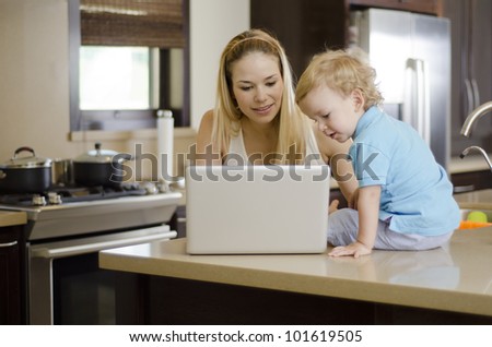 Young beautiful mother showing something to her son in her laptop