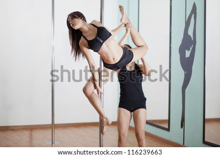 Pole fitness instructor helping a student do a pose