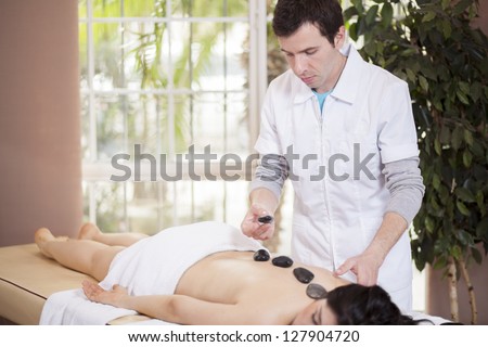 Latin male therapist giving a stone massage to a customer