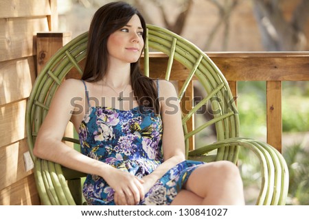 Cute young woman sitting on a rocking chair on a log cabin\'s deck
