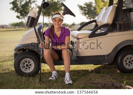 Beautiful Latin golfer sitting in a golf cart and smiling