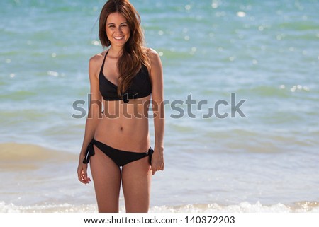 Portrait of a cute Hispanic woman in a bikini getting into the ocean