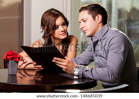 Cute young couple looking at a menu and deciding what to order at a coffee shop